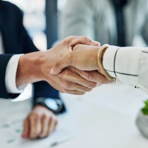 Close-up on 2 professionals shaking hands in the office.